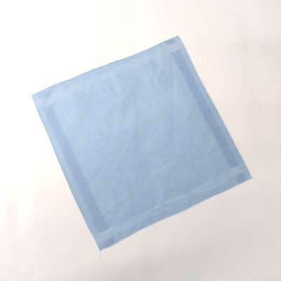 Pano azul claro quadrado com bordas costuradas numa superfície branca