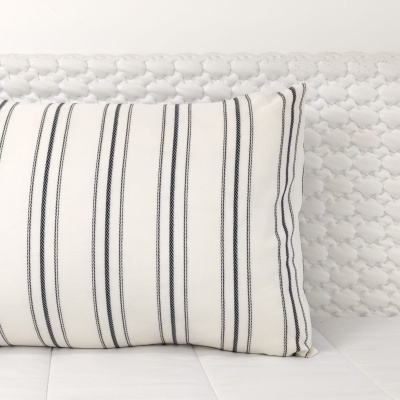 Almofada branca com riscas pretas numa superfície branca texturizada
