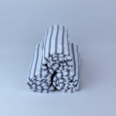 Toalhas brancas com riscas azuis enroladas e empilhadas