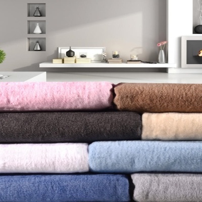 Pilha de mantas felpudas de várias cores em sala moderna com lareira