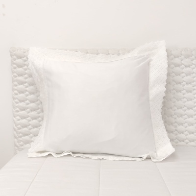 Travesseiro branco com fronha rendada sobre cama branca texturizada