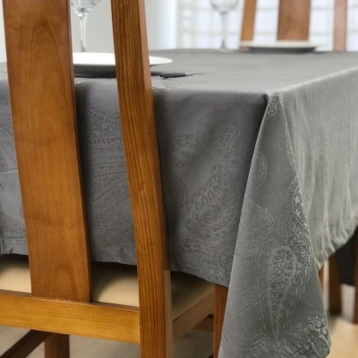 Mesa de madeira com toalha cinza com padrão floral e cadeiras de madeira