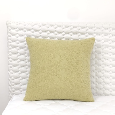 Almofada verde clara com padrão arabesco numa cama branca acolchoada