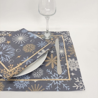 Lugar americano e guardanapo com padrão de flocos de neve, prato branco, talheres de metal e taça de vidro