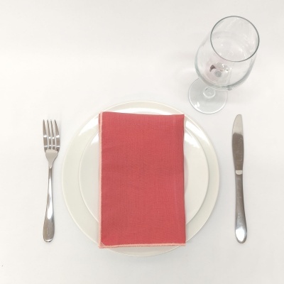 Conjunto de jantar com talheres, pratos brancos e guardanapo vermelho sobre toalha branca