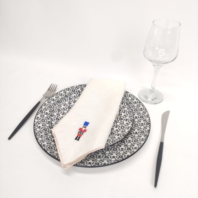 Conjunto de pratos com padrão floral, guardanapo branco bordado, talheres pretos e taça de vidro