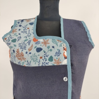 Colete com padrão de folhas coloridas e tecido azul escuro apresentado em manequim preto