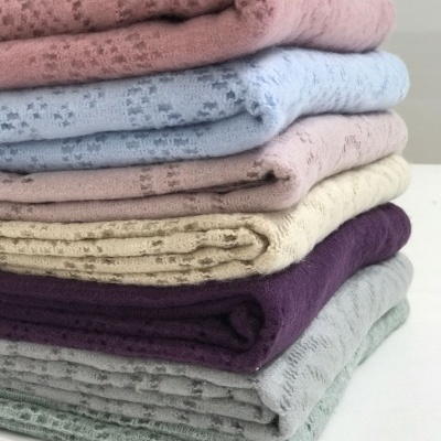 Pilha de mantas dobradas em várias cores pastel com padrão de relevo