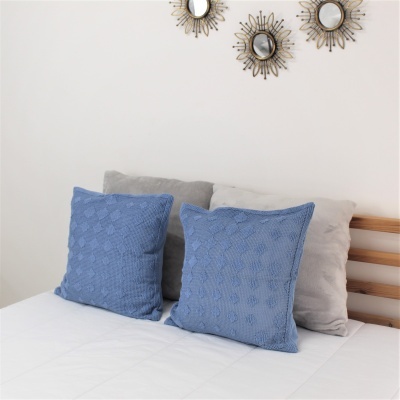 Cama com almofadas azuis e cinza e espelhos redondos decorativos na parede