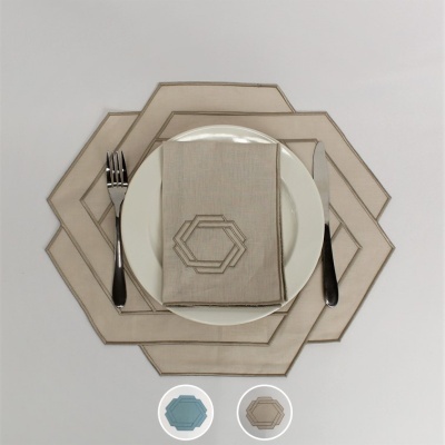 Conjunto de mesa com individuais e guardanapo bege em tecido com padrão geométrico e talheres ao lado