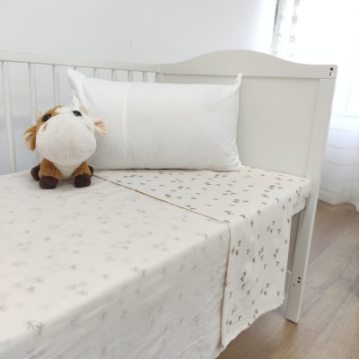 Berço com lençol bege com folhas e peluche de vaca