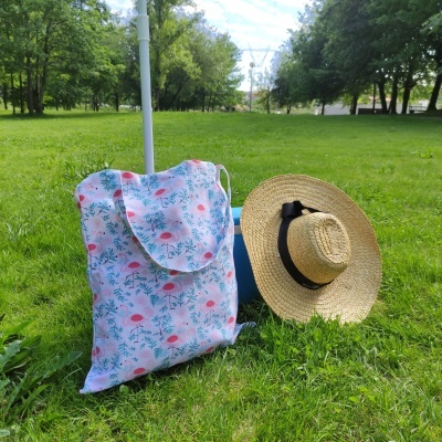 Saco de tecido floral e chapéu de palha na relva