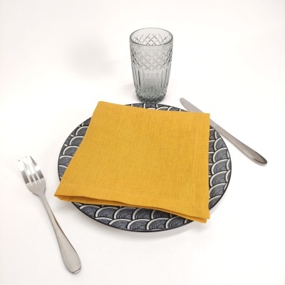 Conjunto de prato, guardanapo amarelo, talheres de metal e copo de vidro