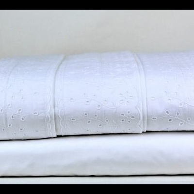 Roupa de cama branca com padrão floral cortado a laser dobrada