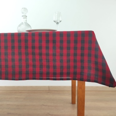 Toalha de mesa xadrez vermelho e preto sobre mesa de madeira com garrafa e vidro
