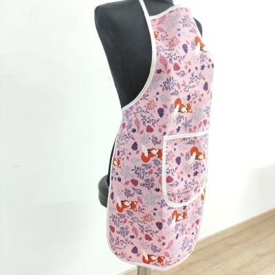 Avental rosa com padrão de raposas e folhas, bolso branco, em manequim preto.