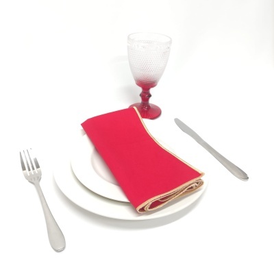 Conjunto de jantar com pratos, guardanapo vermelho, copo transparente e talheres sobre fundo branco