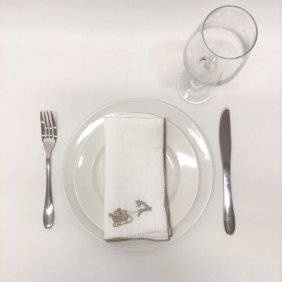 Mesa posta com pratos, guardanapo bordado, talheres e copo