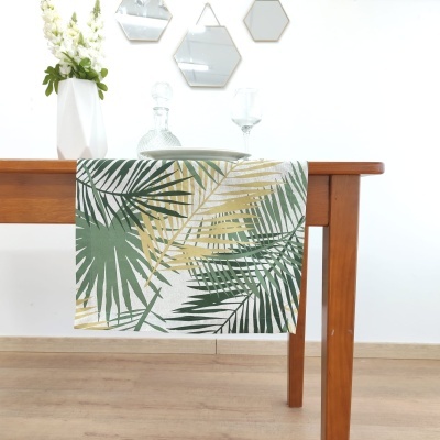 Toalha de mesa com padrão de folhas verdes e douradas pendurada em mesa de madeira