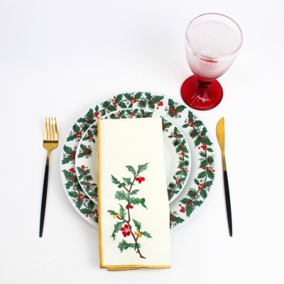 Conjunto de loiça com padrão natalício, talheres dourados com cabo preto e copo vermelho