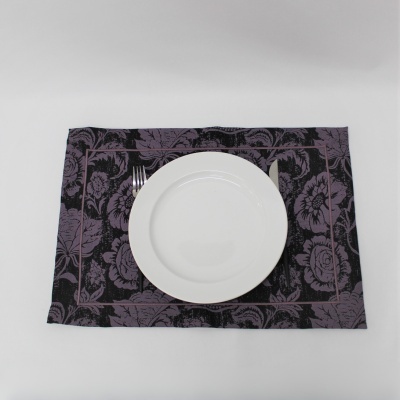 Prato branco sobre individual roxo e preto com padrão floral