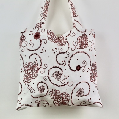 Saco de tecido branco com padrão decorativo castanho e alças estampadas