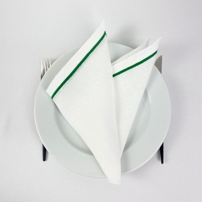 Guardanapo branco com risca verde dobrado sobre prato branco com talheres ao lado