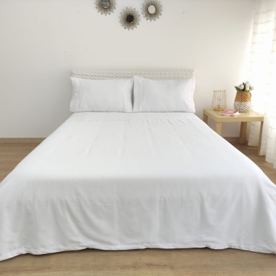 Cama de casal com colcha e fronhas brancas em quarto minimalista