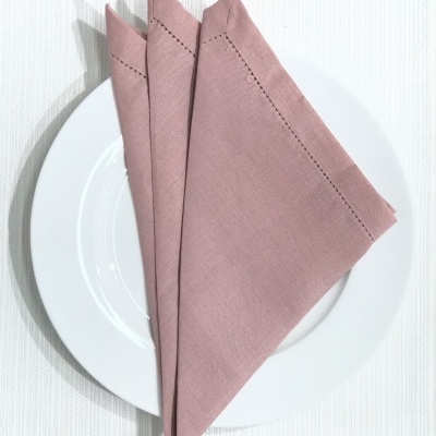 Guardanapo rosa tecido liso dobrado num prato branco