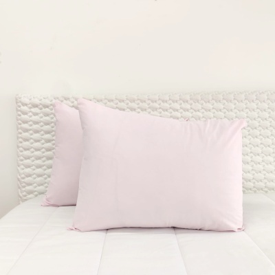 Almofadas cor-de-rosa claro em cama com cabeceira trançada branca