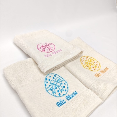 Toalhas brancas com bordados de Páscoa em rosa, amarelo e azul