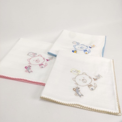 Três fraldas de tecido branco com bordas rosa, azul e bege e bordados de ursinho e pássaro.