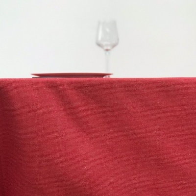 Toalha vermelha sobre mesa de madeira com copo de vidro ao fundo