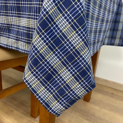 Toalha de mesa xadrez azul e branco pendurada numa mesa de madeira clara