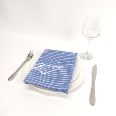 Conjunto de mesa com talheres, prato branco, guardanapo azul listrado com concha branca e taça de vidro