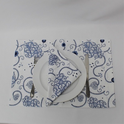 conjunto de mesa com prato branco, talheres prateados e guardanapo e toalhete de tecido branco com padrões azuis