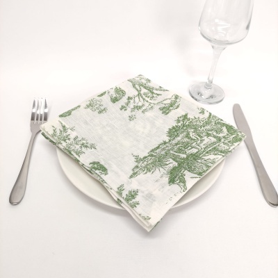 Mesa posta com guardanapo estampado verde sobre prato branco, talheres de metal e copo de vidro