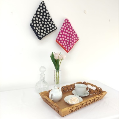 Bandeja de madeira com utensílios para chá sobre mesa branca e toalhas de cozinha coloridas penduradas na parede