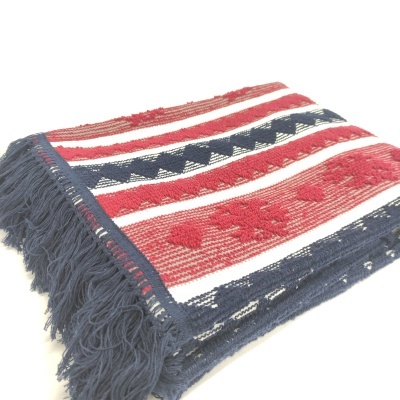 Manta dobrada com franjas e padrão vermelho, branco e azul.