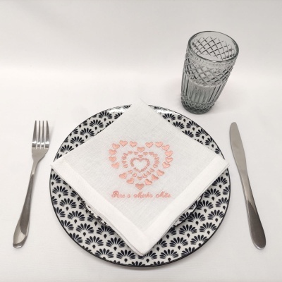 Conjunto de mesa com prato, guardanapo bordado, talheres e copo em fundo branco