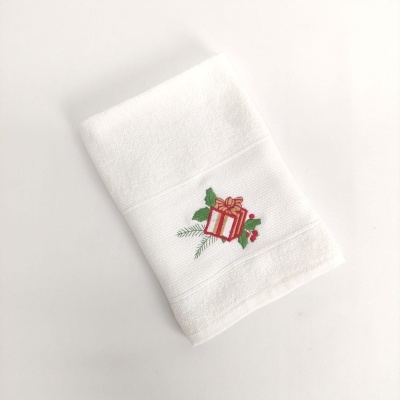 Toalha branca com bordado de presente e folhas verdes