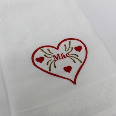 Toalha branca com bordado de coração e palavra Mãe.