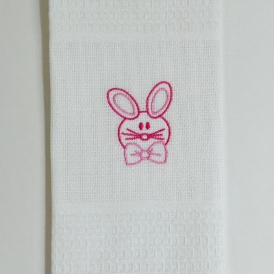 Toalha branca com bordado rosa de um coelho com laço