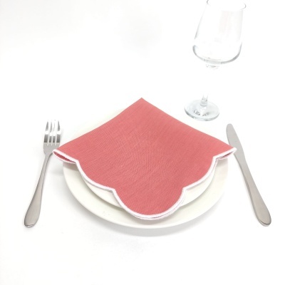 Guardanapo vermelho com borda branca ondulada em prato branco com talheres e copo