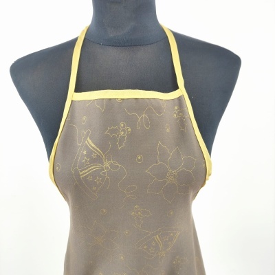 Avental cinza com padrão amarelo claro de sinos e flores e acabamento amarelo em manequim preto