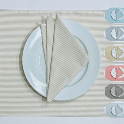 Jogo americano bege riscado com guardanapo combinado e amostras de cores variadas à direita