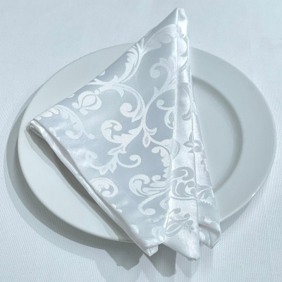 Guardanapo branco estampado em prato branco sobre mesa branca