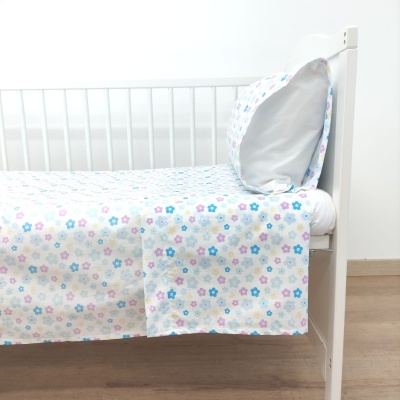 Cama branca com roupa de cama estampada de flores coloridas