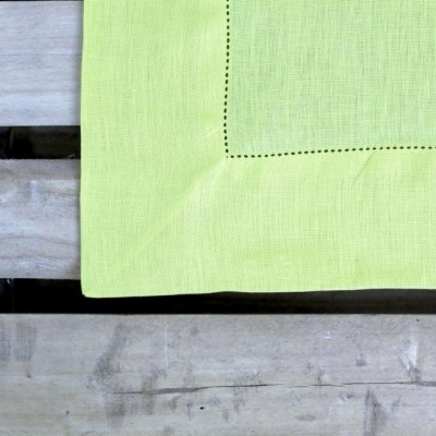 toalha de mesa verde clara com borda de pontos pretos sobre tábuas de madeira