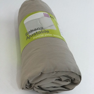 Sábana ajustable beige enrollada con etiqueta verde